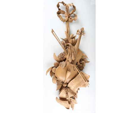 A 20th century carved wooden wall appliqué, modelled in the form of a violin and bow supported by a scroll of music, fruit, f