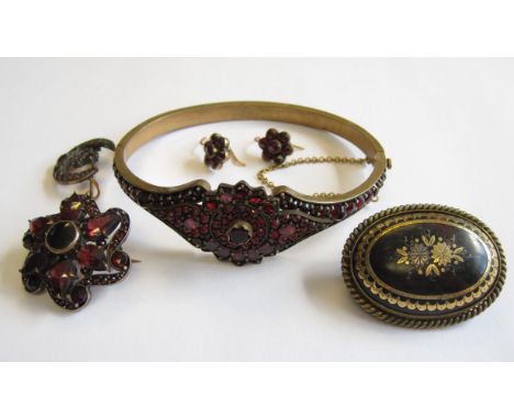 An oval Tortoiseshell Brooch with piqué decoration, a Garnet hinged Bangle, two Garnet Brooches and a pair of Garnet flower c