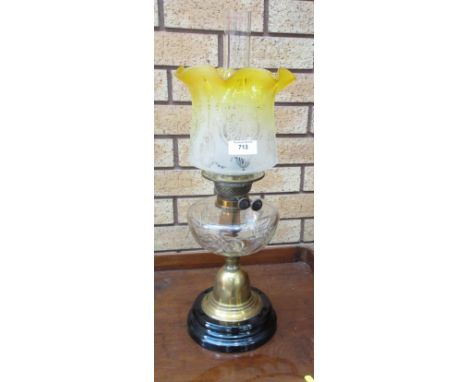 A brass Oil Lamp with cross hatched glass reservoir and yellow ground shade