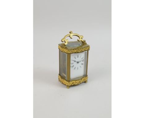 A French brass Carriage Clock with white enamel dial and cast gilt metal decoration of scrolls to the upper and lower frieze,