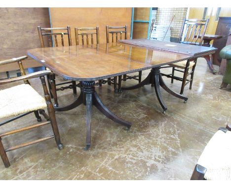 A 19th Century Sheraton style mahogany two-pillar Dining Table having reeded top, with two spare leaves on turned columns wit