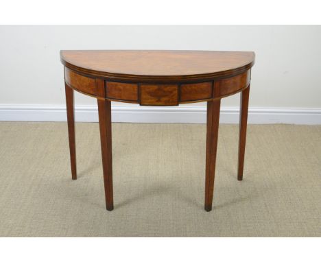 A Sheraton satinwood demi-lune Tea Table with fold-over top having cross-banding and stringing above urn inlaid frieze on squ