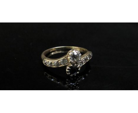 A gold diamond and sapphire cross-over ring with diamond set shoulders, stamped 18ct (rubbed). Size R, 3.4g 
