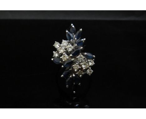 An 18ct white gold diamond and sapphire dress ring, 12 brilliant cut diamonds and 12 marquis cut sapphires. Size P, 8.2g with