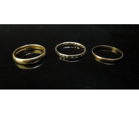 Two 22ct gold bands, sizes O and P, 5.4g and an eternity ring, unmarked. Size R, 1.5g 