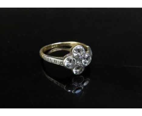 A gold ring with four 0.20ct approx diamonds in floral shape, small diamond to centre and diamond set shoulders, stamped 18ct