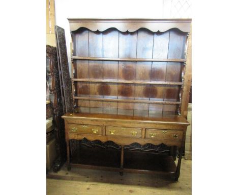 An Antique style oak dresser, with close boarded rack rack, the base fitted with three drawers over a shelf uniting the legs,