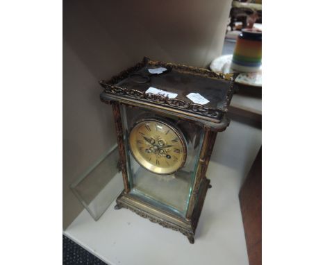 A late Victorian/Edwardian brass mantel/carriage clock having scroll gallery and blind fret pendulum on bracket feet