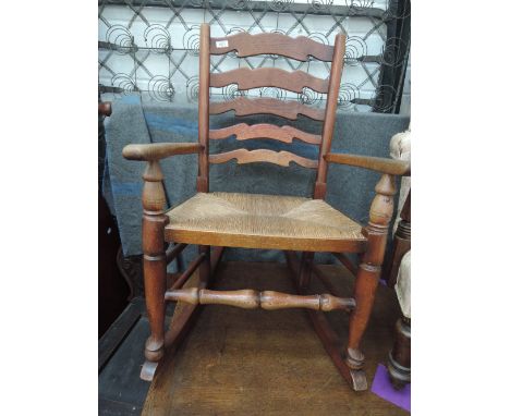 A 20th century oak rocking chair having ladder back and rush seat