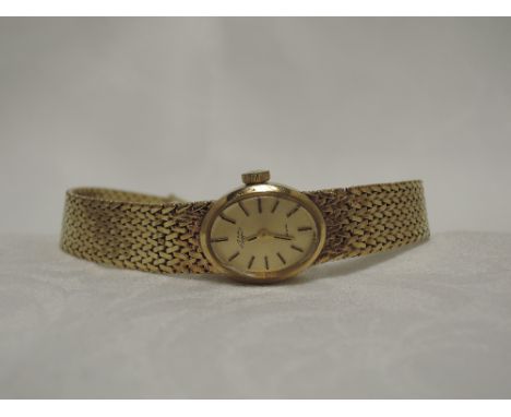 A ladies 9ct gold wrist watch by Rotary having a baton numeral dial to an oval face on a 9ct gold woven strap