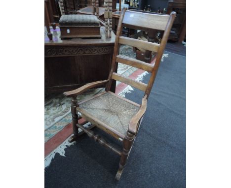 A 19th century stained frame rocking chair having ladder back and rush seat