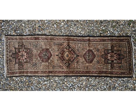 A Persian Turkoman runner, the geometric design on a brown ground with guarded border, 183 x 59 cm