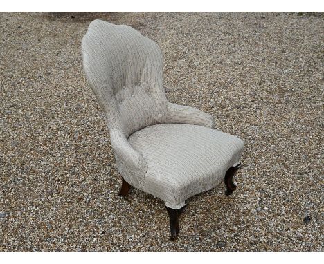 A Victorian mahogany framed button back chair with floral/striped upholstery, shaped front legs and brass castors