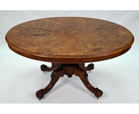 A Victorian walnut oval tilt top breakfast table raised on a moulded turned pillar to four moulded legs on ceramic castors, 1