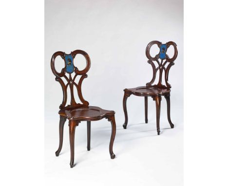 A Pair of George III Mahogany Hall Chairs in the Manner of Chippendale  the pierced scroll backs centred by painted armorial 