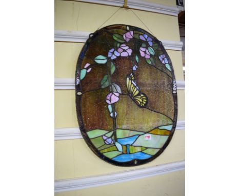 A stained glass panel of a butterfly in a landscape, inscribed 'interior, 1900', 60.5 x 46cm oval.  