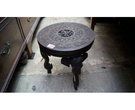 An Indian carved hardwood small occasional table, with three elephant trunk supports, 30cm wide.