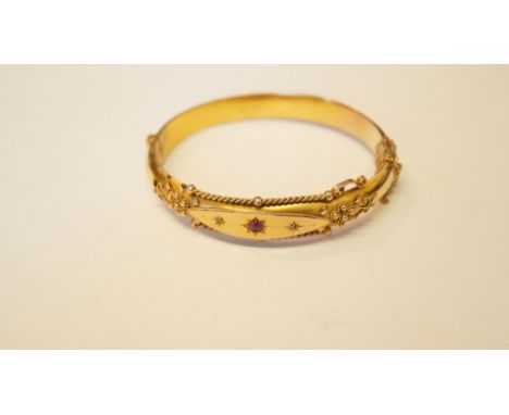 A late Victorian 9ct gold hinged bangle, decorated filigree, ruby and diamond chips.