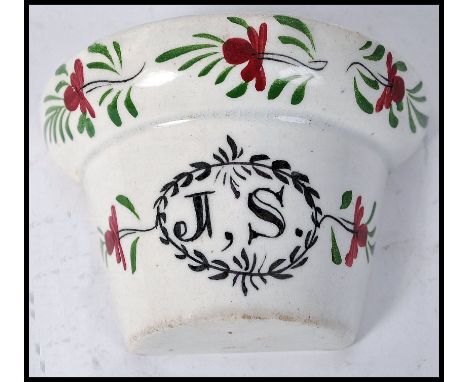 A delicate small 18th century ceramic bird feeder trough being wall mounted and in the form of a plant pot with chintz patter