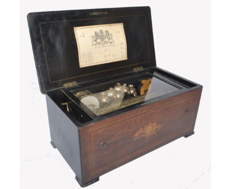 A 19th century rosewood and marquetry inlaid music box. The brass cylinder playing eight Airs, the titles handwritten on a co