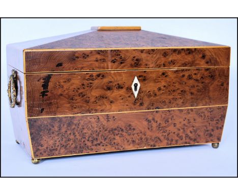 A 19th century George III amboyna wood tea caddy of sarcophagus form with line inlaid details. Raised on brass finial feet wi