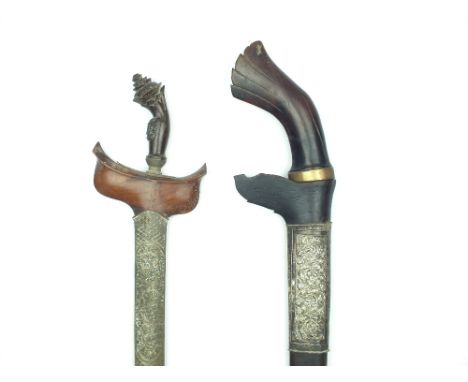 A Malayan Bade-Bade, 47cm watered steel blade, characteristic carved wooden hilt, contained in its embossed white metal wrapp