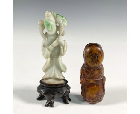 Two carved jade figures, one brown jade and other is white with splashes of green. Carved from jade, one is depicted standing