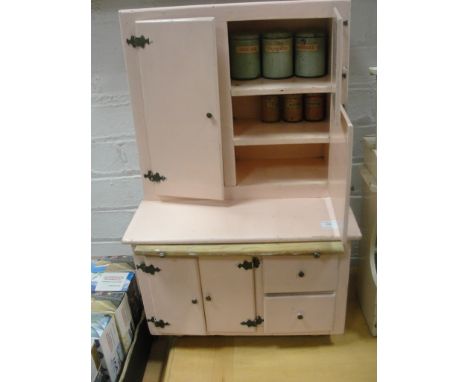 A toy kitchen cabinet containing an enamel tin, flour sifter etc