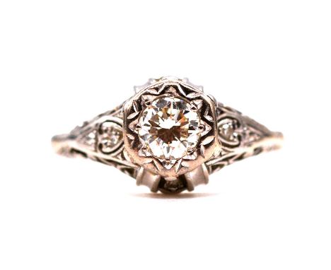 A diamond solitaire ring, the brilliant cut stone illusion set in an all white metal mount ring size O, ornate shoulders and 