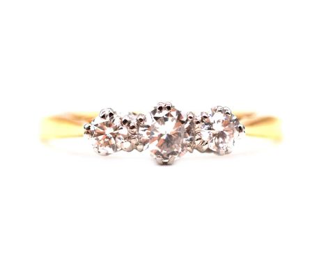 A diamond three stone ring, the brilliant cut stones claw set in a yellow and white metal mount ring size P, shank marked 18c
