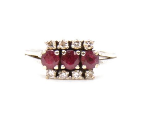 A ruby and diamond triple row ring, three rubies claw set horizontally and bordered by four brilliant cut diamonds to top and