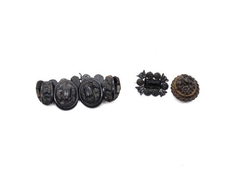 A faux jet panel bracelet and two faux jet brooches, a faux jet panel bracelet with eleven floral design carved panels, gradu