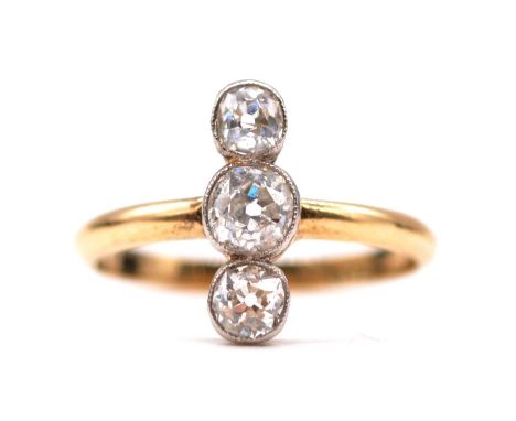 A diamond three stone ring, the old brilliant cut stones individually millegrain set vertically in a yellow and white metal m