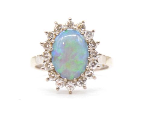 A opal and diamond cluster ring, the oval cabochon cut opal claw set and surrounded by sixteen brilliant cut diamonds in an 1