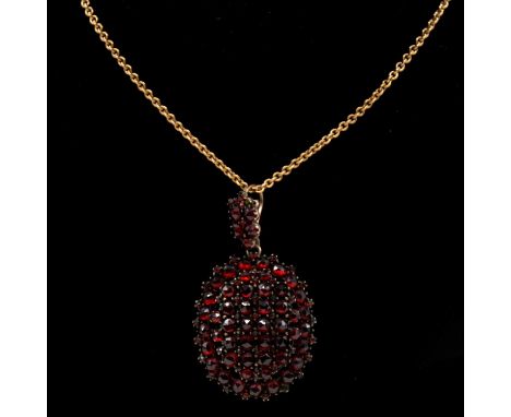 An oval gemset pendant and chain, the oval yellow metal pendant, 35x30mm, pave set with multiple rose cut garnet coloured sto