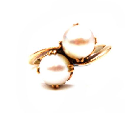 A cultured pearl crossover ring, the two cultured pearls, 7.7 and 7.5mm, double claw set in a yellow metal mount size M, shan
