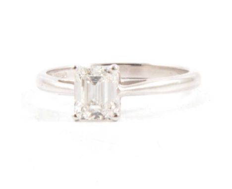 A diamond solitaire ring, the emerald cut stone four claw set in an 18 carat white gold mount, 2mm wide shank ring size O, Bi