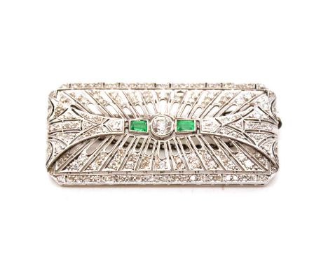 An Art Deco emerald and diamond brooch, a major old cut diamond collet set to the centre with a rectangular emerald to each s