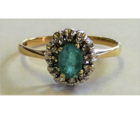 A 9ct gold emerald and diamond cluster ring claw set with a mixed cut stone bordered by single cuts