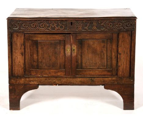 A JOINED OAK CUPBOARD, INCORPORATING A CARVED FRIEZE CENTRED BY INITIALS A S AND DATE 1713, ON BRACKET FEET, THE CHAMFERED TO