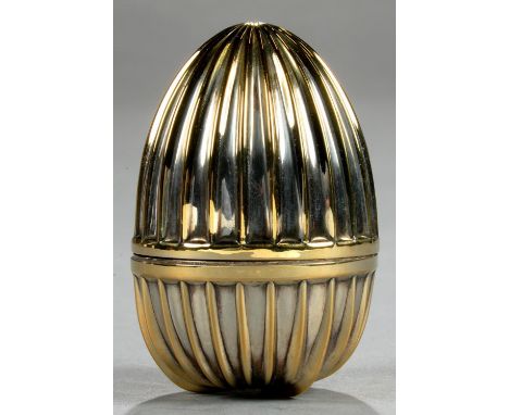 AN ELIZABETH II FLUTED SILVER GILT EGG, THE LID OPENING TO REVEAL LILY OF THE VALLEY 'SURPRISE', ON RADIANT GREEN ENAMEL BASE
