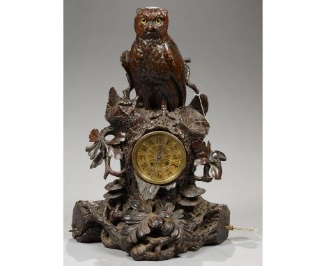 A SWISS 'BLACK FOREST' CARVED AND STAINED LIMEWOOD MUSICAL CLOCK IN THE FORM OF AN OWL PERCHED ON A RUSTIC TREE TRUNK, FLANKE