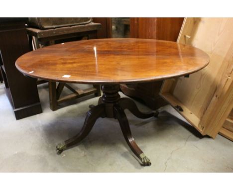 19th century Oval Tilt Top Loo / Centre Table raised on a turned column support and four reeded splay legs, brass paw feet an