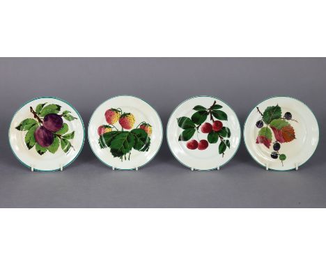 A set of four Wemyss pottery 5½” side plates with green borders on a cream ground, painted with plums, strawberries, blackber