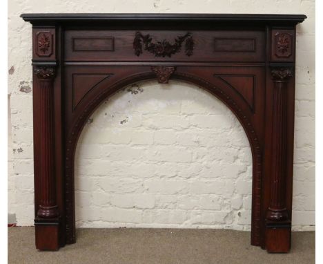 A carved mahogany effect fire surround with reeded columns and floral swags.