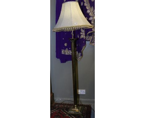 A brass fluted Corinthian column standard lamp raised on a square stepped plinth over paw feet.