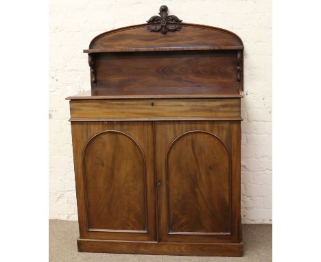 A Victorian mahogany chiffonier with arched top having carved pediment and a single shelf raised on scrolling corbels.