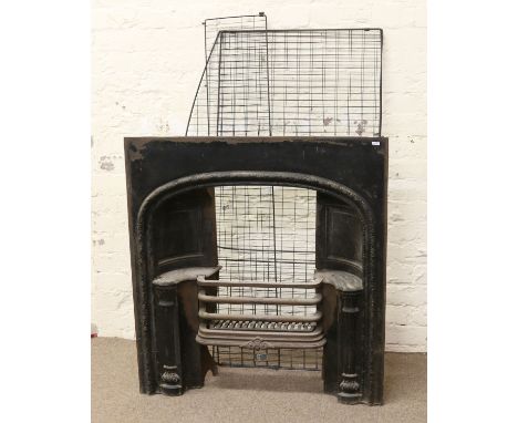 A Victorian cast iron fire insert ornamented with fluted column supports and a wire fireguard.