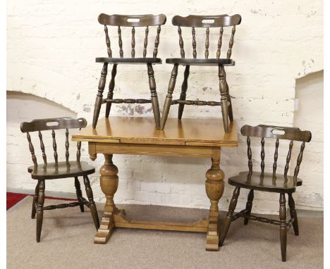 A light oak drawleaf table raised on twin bulbous legs along with a set of four carved and turned dining chairs.