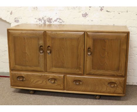 An Ercol Golden Dawn light oak carved sideboard of three doors over two base drawers.
